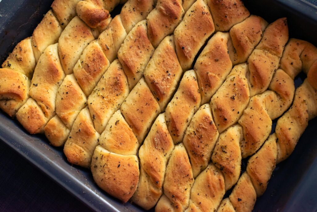 pexels-photo-10902790-10902790 Deliciously baked herb-infused bread twists in a metal tray, golden brown and perfect for any meal.